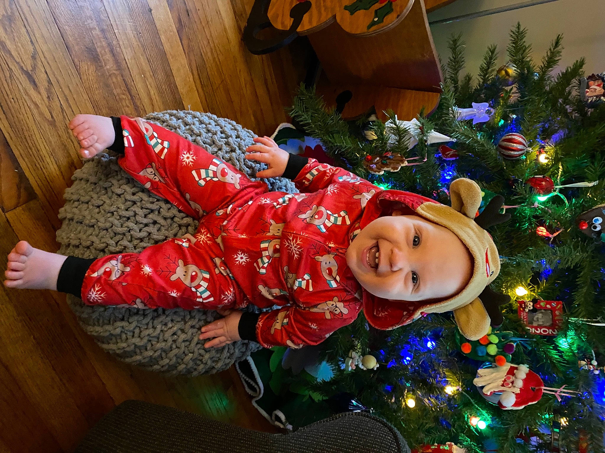 Ellis is registered to the contest to win money with this photo: baby, baby_toddler_clothing, christmas, christmas_decoration, christmas_eve, christmas_lights, christmas_ornament, christmas_tree, conifer, headwear, holiday, holiday_ornament, human, interior_design, joy, lap, nightwear, ornament, pajamas, person