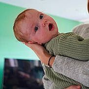 Gabin participe au concours pour gagner de l'argent avec cette photo : adult, baby, child, closeup, curious, expression, face, green, hand, holding, home, human, indoor, knitwear, person, portrait, skin, soft_light, surprised, sweater