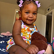 Malonni joined the competition — help win amazing prizes! toddler, child, smiling, curly_hair, bows, plush_toy, bed, floral_outfit, indoor, happy, portrait, candid, skin, cute, baby, person, clothing, furniture, room, comfort