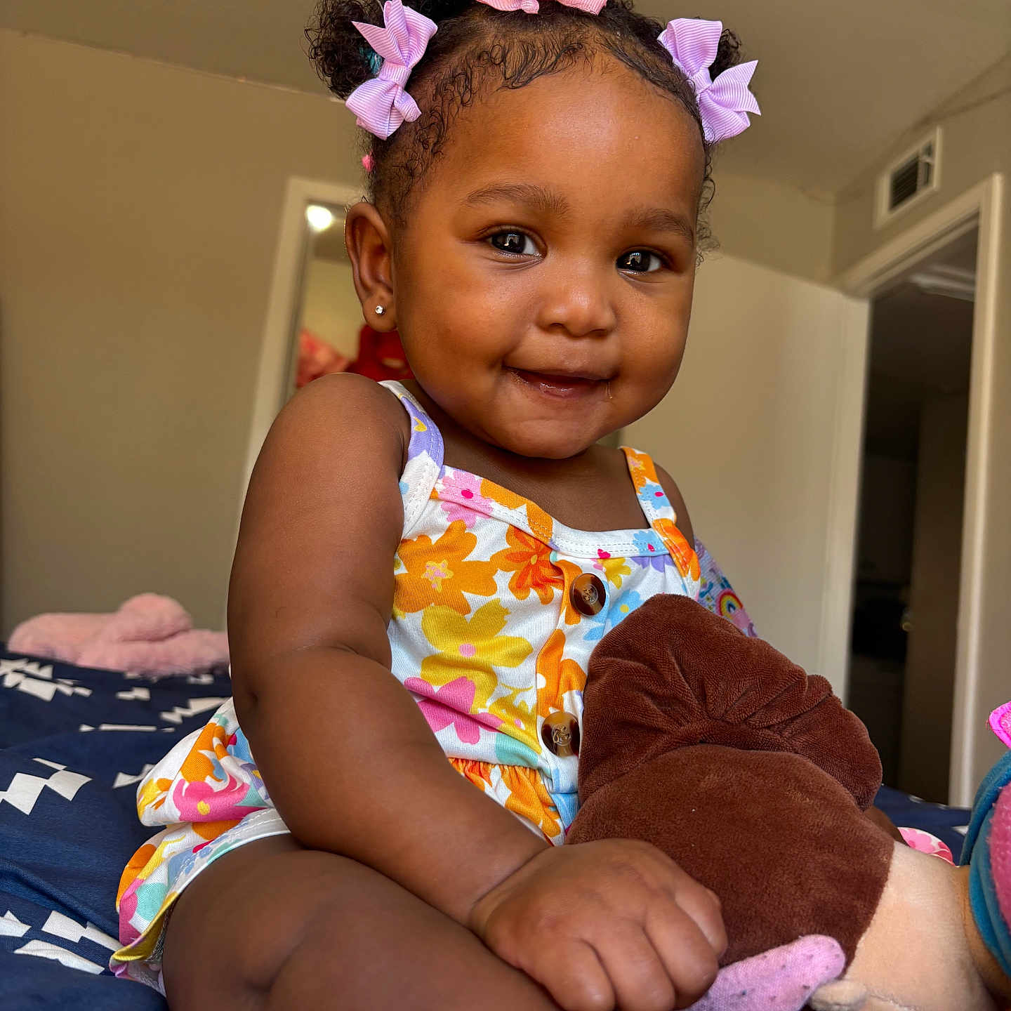 Malonni joined the competition — help win amazing prizes! toddler, child, smiling, curly_hair, bows, plush_toy, bed, floral_outfit, indoor, happy, portrait, candid, skin, cute, baby, person, clothing, furniture, room, comfort