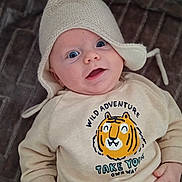 Lewis a rejoint le concours — aidez-le/la à gagner de superbes lots ! baby, infant, hat, knit_hat, pom_pom, sweatshirt, cartoon_tiger, text_on_clothing, smiling, blue_eyes, blanket, patterned_blanket, star_pattern, cozy, cute, child, person, portrait, indoors, happy