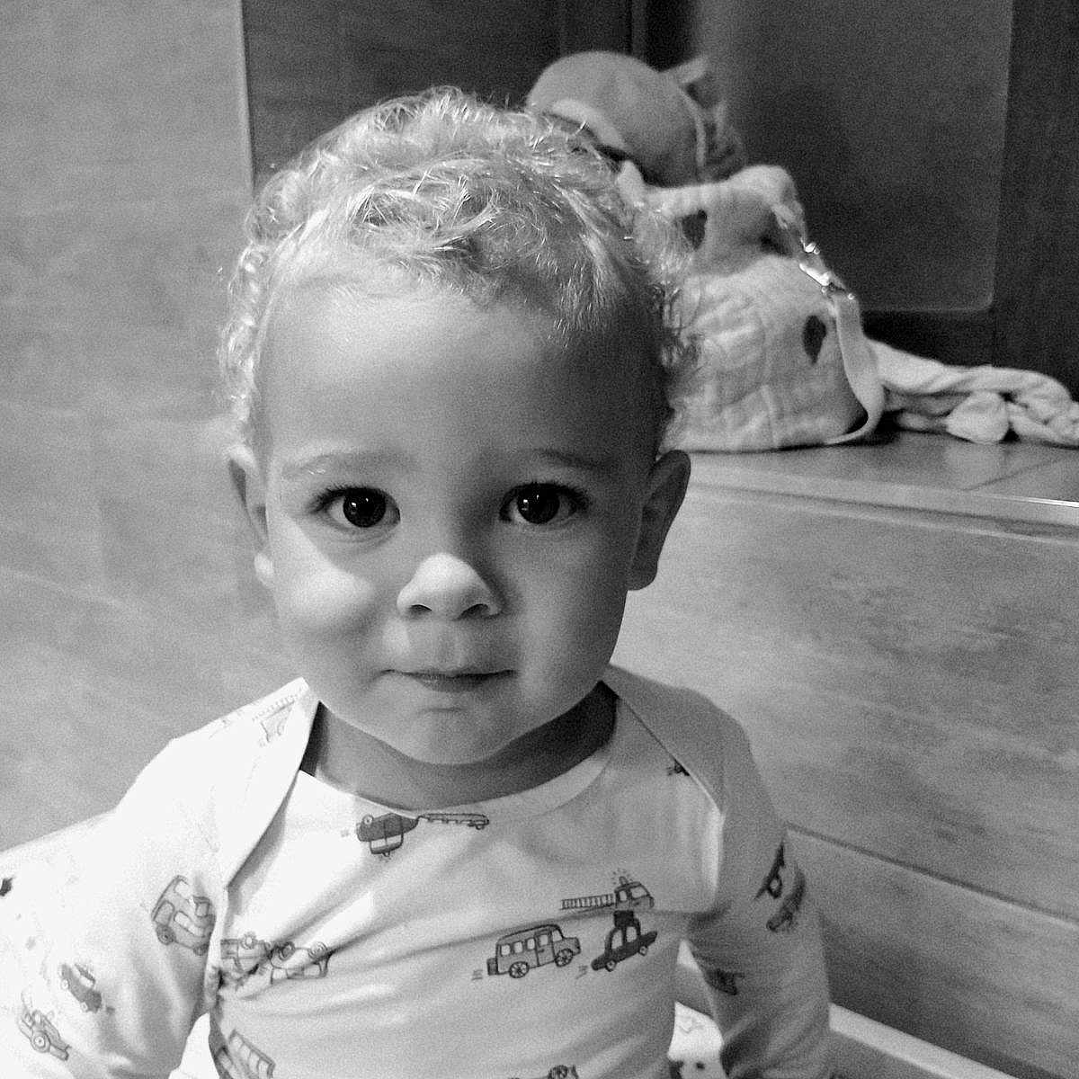 Pharell participe au concours pour gagner de l'argent avec cette photo : baby, bed, black_and_white, child, close_up, clothing, curly_hair, cute, expression, face, indoor, monochrome, pajamas, person, portrait, sitting, soft_lighting, toddler, toy, young_child