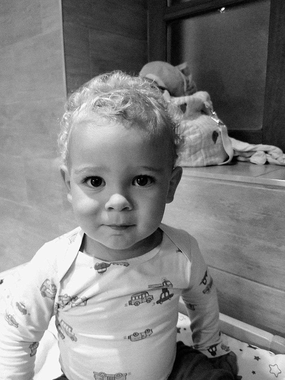 Pharell participe au concours pour gagner de l'argent avec cette photo : toddler, child, curly_hair, pajamas, indoor, portrait, cute, baby, face, expression, clothing, person, young_child, sitting, bed, toy, soft_lighting, monochrome, black_and_white, close_up