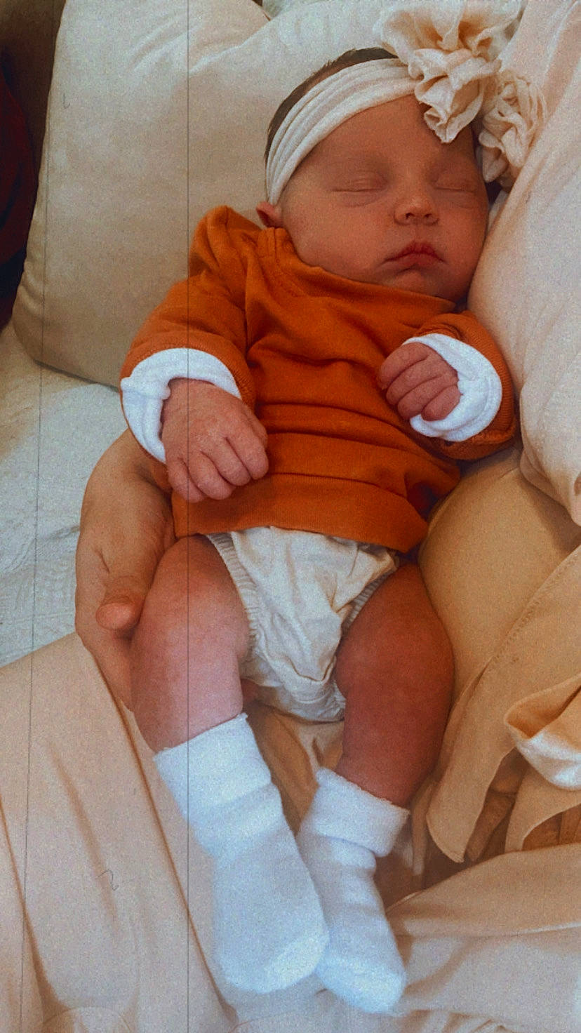 Charlie is registered to the contest to win money with this photo: arm, baby, cheek, chest, comfort, diaper, eye, finger, hand, head, headwear, human_body, knee, mouth, muscle, person, skin, stomach, thigh, thumb