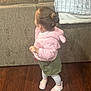 toddler, child, indoor, floor, wooden_floor, couch, blanket, hairclip, pink_jacket, green_skirt, white_tights, shoes, standing, person, furniture, home, cozy, cute, looking_sideways, young_child
