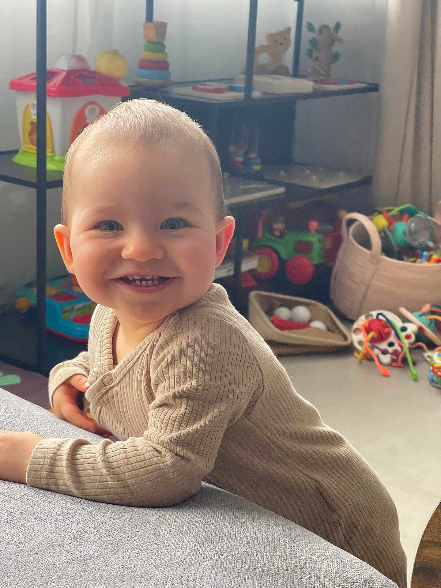Olivia participe au concours pour gagner de l'argent avec cette photo : baby, smile, blue_eyes, toys, indoor, child, happy, sweater, furniture, shelf, playroom, curious, leaning, soft_surface, cute, portrait, infant, home, colorful, young_child