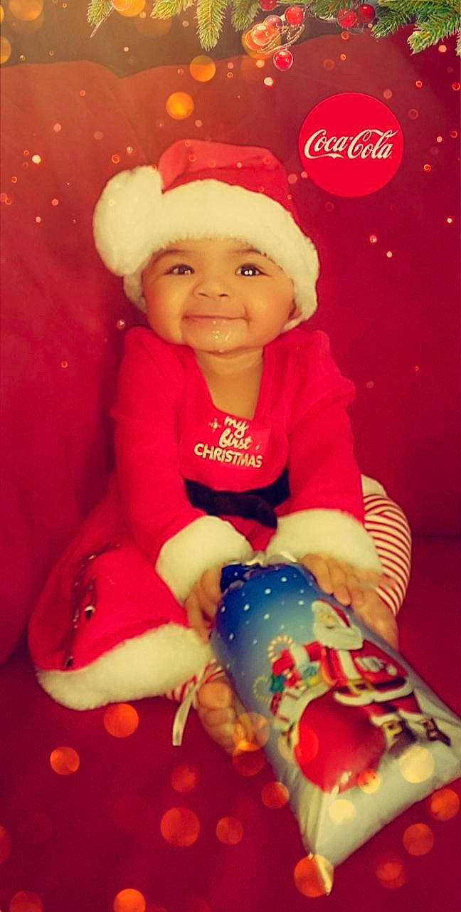 Lailah is registered to the contest to win money with this photo: baby, baby_playing_with_toys, baby_toddler_clothing, baby_toys, bonnet, christmas, christmas_eve, costume_accessory, costume_hat, fictional_character, headwear, holiday, joy, lap, person, pleased, red, santa_claus, sock, toy