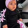 baby, child, infant, black_clothing, pink_bows, headband, flower, car_seat, blanket, pink_and_white, cute, portrait, indoors, small_hand, curious_expression, sitting, face, eyes, lips, cozy