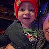 Carter joined the competition — help win amazing prizes! child, toddler, smiling, red_hat, beanie, indoor, television, adult, holding, jacket, green_shirt, happy, face, person, cozy, warm_clothing, hand, living_room, cute, portrait