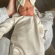 Dolcie Mae joined the competition — help win amazing prizes! baby, newborn, sleeping, bow, headband, hand, cozy, ribbed_clothing, cream_color, infant, peaceful, soft, warm, closeup, portrait, child, indoors, resting, human, cute