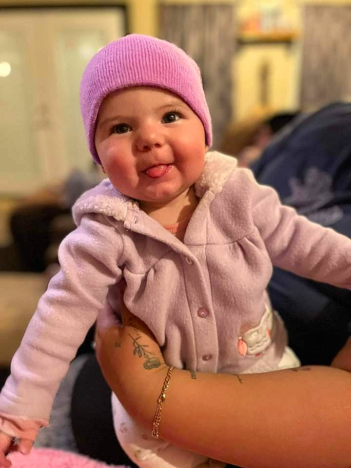 Roxanne joined the competition — help win amazing prizes! baby, baby_toddler_clothing, cap, cheek, child, comfort, fun, gesture, happy, headwear, jewellery, knit_cap, magenta, person, sitting, skin, sleeve, smile, thumb, toddler