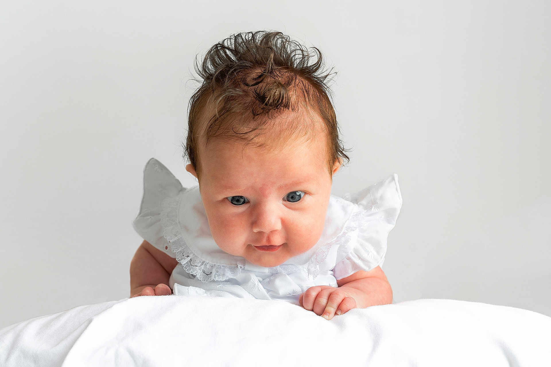 Penelope joined the competition — help win amazing prizes! baby, infant, child, portrait, white_clothing, lace, blanket, curly_hair, blue_eyes, closeup, cute, soft_light, studio, neutral_background, expression, hands, skin, face, person, newborn