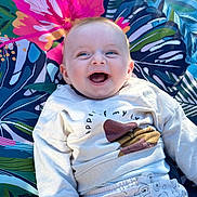 Paul a rejoint le concours — aidez-le/la à gagner de superbes lots ! baby, smiling, blue_eyes, sweatshirt, pants, patterned_clothing, tropical_blanket, colorful, happy, child, infant, portrait, outdoor, sunlight, cute, joyful, lying_down, closeup, face, expression
