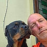 black_and_tan, building, closeup, companion, dog, doorway, eyes, facial_expression, fur, man, nose, outdoor, pet, photography, portrait, red_shirt, rottweiler, selfie, squinting, wall