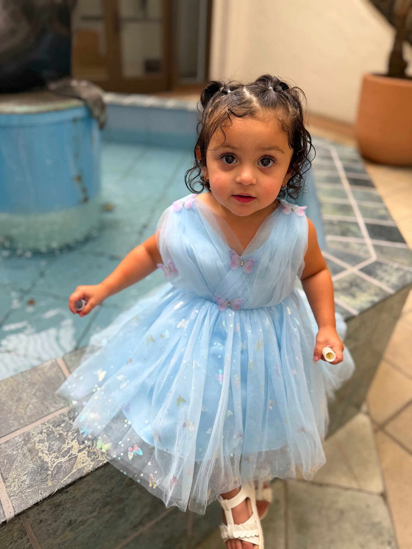 Paisley joined the competition — help win amazing prizes! child, toddler, girl, blue_dress, dress, fountain, water, tiles, curly_hair, ponytails, sandals, eyes, face, portrait, standing, holding, white_object, courtyard, cute, sparkles