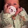 baby, infant, pacifier, hand, pink_nail_polish, onesie, floral_pattern, face, eyes, clothing, sleepwear, cute, child, newborn, soft_lighting, portrait, indoors, fabric, fingers, nail_polish