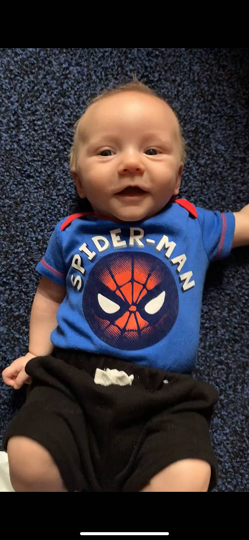 Dallas is registered to the contest to win money with this photo: baby, baby_toddler_clothing, child, electric_blue, fictional_character, fun, happy, human_body, logo, orange, person, personal_protective_equipment, play, player, sitting, sleeve, smile, soccer_ball, spider_man, t_shirt