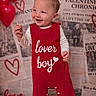 toddler, child, baby, red_romper, lover_boy, smiling, standing, white_socks, background_newspapers, valentine, heart, red_balloons, indoor, portrait, cute, happy, clothing, baby_boy, studio_photo, infant