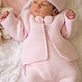 baby, infant, pink_clothing, knitwear, hat, pom_pom, blanket, soft_texture, sleepwear, newborn, cute, child, portrait, resting, indoors, warm, cozy, hands, feet, peaceful