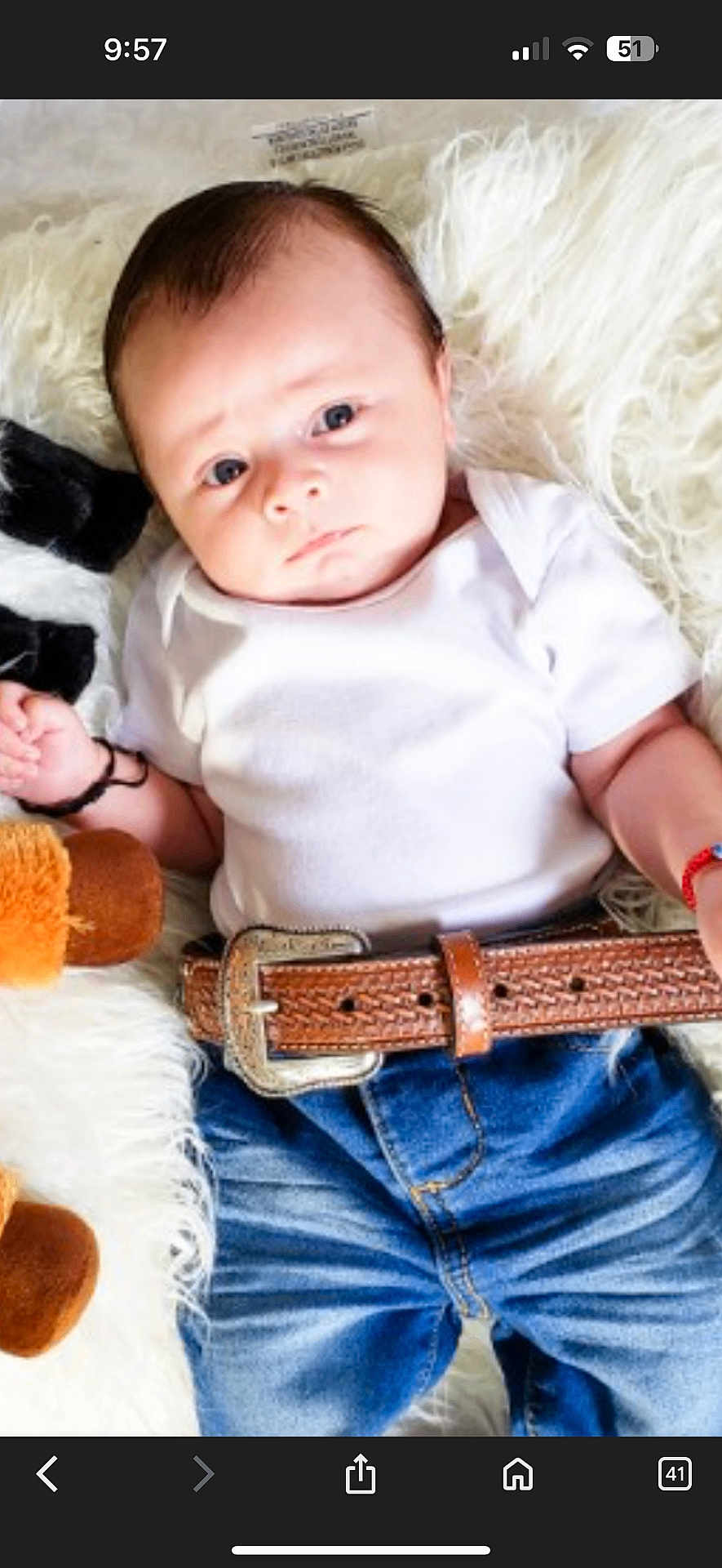 Megan joined the competition — help win amazing prizes! baby, infant, child, white_onesie, blue_jeans, brown_belt, plush_toy, fluffy_blanket, lying_down, cute, curious, indoor, portrait, small_hands, soft_texture, young_child, casual_clothing, human, face, blue_eyes