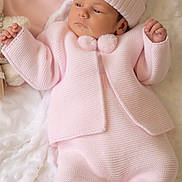 Megan is registered to the contest to win money with this photo: baby, infant, pink_clothing, knitwear, hat, pom_pom, blanket, soft_texture, sleepwear, newborn, cute, child, portrait, resting, indoors, warm, cozy, hands, feet, peaceful