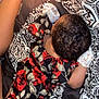 baby, infant, floral_clothing, blanket, birthday_candle, cupcake, pattern, sleeping, lying_down, arm, leg, diaper, curly_hair, celebration, bed, soft_lighting, close_up, indoors, child, cute