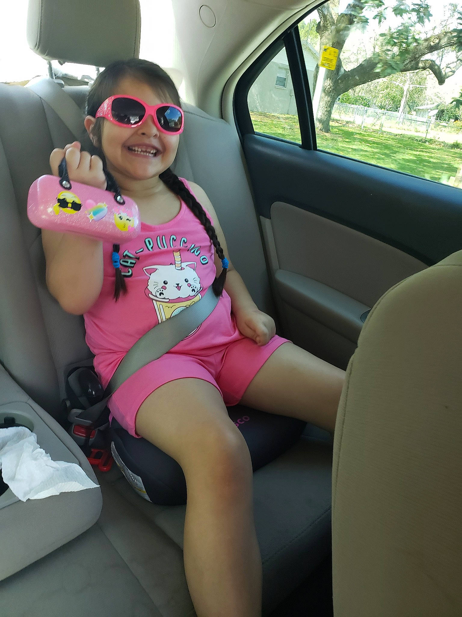Emma Jean is registered to the contest to win money with this photo: auto_part, black_hair, car, car_seat, car_seat_cover, city_car, eyewear, family_car, glasses, head_restraint, joy, person, pink, plant, seat_belt, sunglasses, vacation, vehicle, vehicle_door