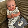 Sacha a rejoint le concours — aidez-le/la à gagner de superbes lots ! baby, smiling, infant, couch, onesie, patterned_clothing, milestone_card, indoor, face, hand, happy, sitting, textile, green, cute, portrait, child, person, home, cozy