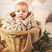 Lyla joined the competition — help win amazing prizes! baby, blanket, basket, blue_eyes, cozy, cushion, face, furniture, greenery, handwoven, infant, indoors, light_skin, natural_light, person, plush, portrait, soft_texture, woven, wooden