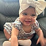 baby, infant, smiling, headband, bow, dress, floral_pattern, crawling, shoes, leather_chair, cute, happy, child, indoors, person, apparel, footwear, tongue, hand, skin