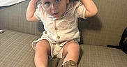 Christopher is registered to the contest to win money with this photo: toddler, child, cowboy_hat, hat, sitting, couch, indoor, curious, casual_clothing, shoes, brown, beige, portrait, young_child, person, furniture, home, cute, small_child, expression