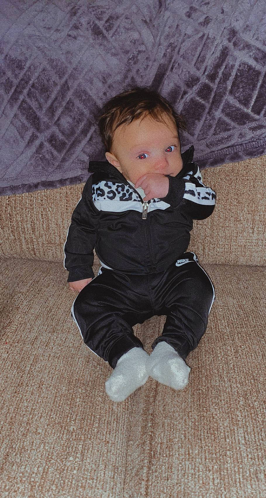 Ily is registered to the contest to win money with this photo: baby, baby_toddler_clothing, brown, cheek, comfort, eye, finger, floor, flooring, fun, head, human_body, iris, leg, person, sitting, skin, sleeve, sock, toddler