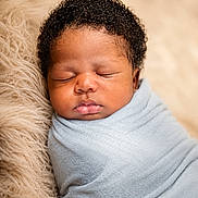 Kashton Dixon is registered to the contest to win money with this photo: baby, newborn, sleeping, wrapped, blanket, curly_hair, face, infant, soft_texture, closeup, peaceful, cute, portrait, skin, head, resting, child, cozy, warm, indoors