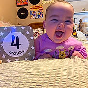 Olivia joined the competition — help win amazing prizes! 4_months, album_covers, baby, bed, blanket, child, cozy_room, cute, happy, indoor, infant, person, pink_sweater, portrait, sign, smiling, vinyl_records, wall, winnie_the_pooh, wooden_headboard