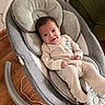 baby, infant, smile, onesie, baby_rocker, cushion, wooden_floor, indoor, person, furniture, happy, seat, head, face, cozy, baby_clothing, child, relax, living_room, cute