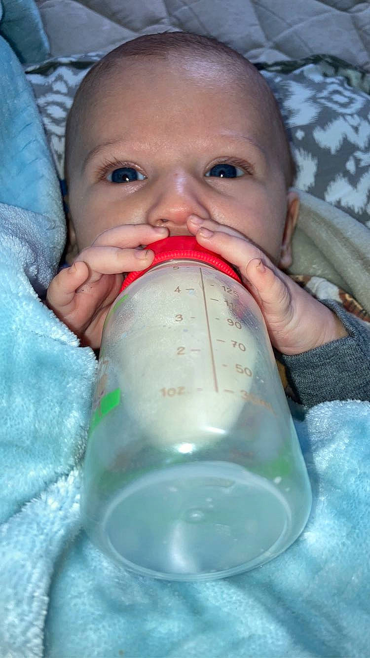 Koa is registered to the contest to win money with this photo: baby, baby_bottle, baby_toddler_clothing, cheek, drink, drinking, drinkware, eyelash, facial_expression, finger, fluid, hand, happy, liquid, mouth, nail, nose, person, plastic_bottle, skin