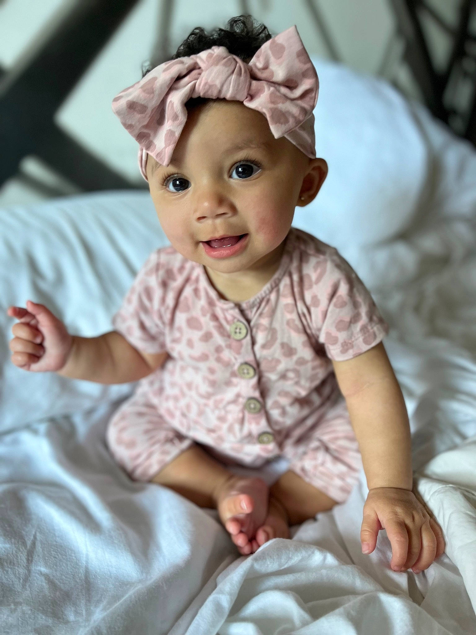 Brixley Sakura Kimberly is registered to the contest to win money with this photo: baby, baby_toddler_clothing, cheek, child, collar, comfort, fashion_accessory, happy, headwear, linens, magenta, pattern, person, photograph, pink, sitting, skin, sleeve, smile, t_shirt
