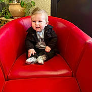 Naël a rejoint le concours — aidez-le/la à gagner de superbes lots ! baby, toddler, child, red_chair, armchair, indoor, potted_plant, plant, smile, face, jacket, socks, clothing, hair, upholstery, wall, doorway, hands, portrait, cozy