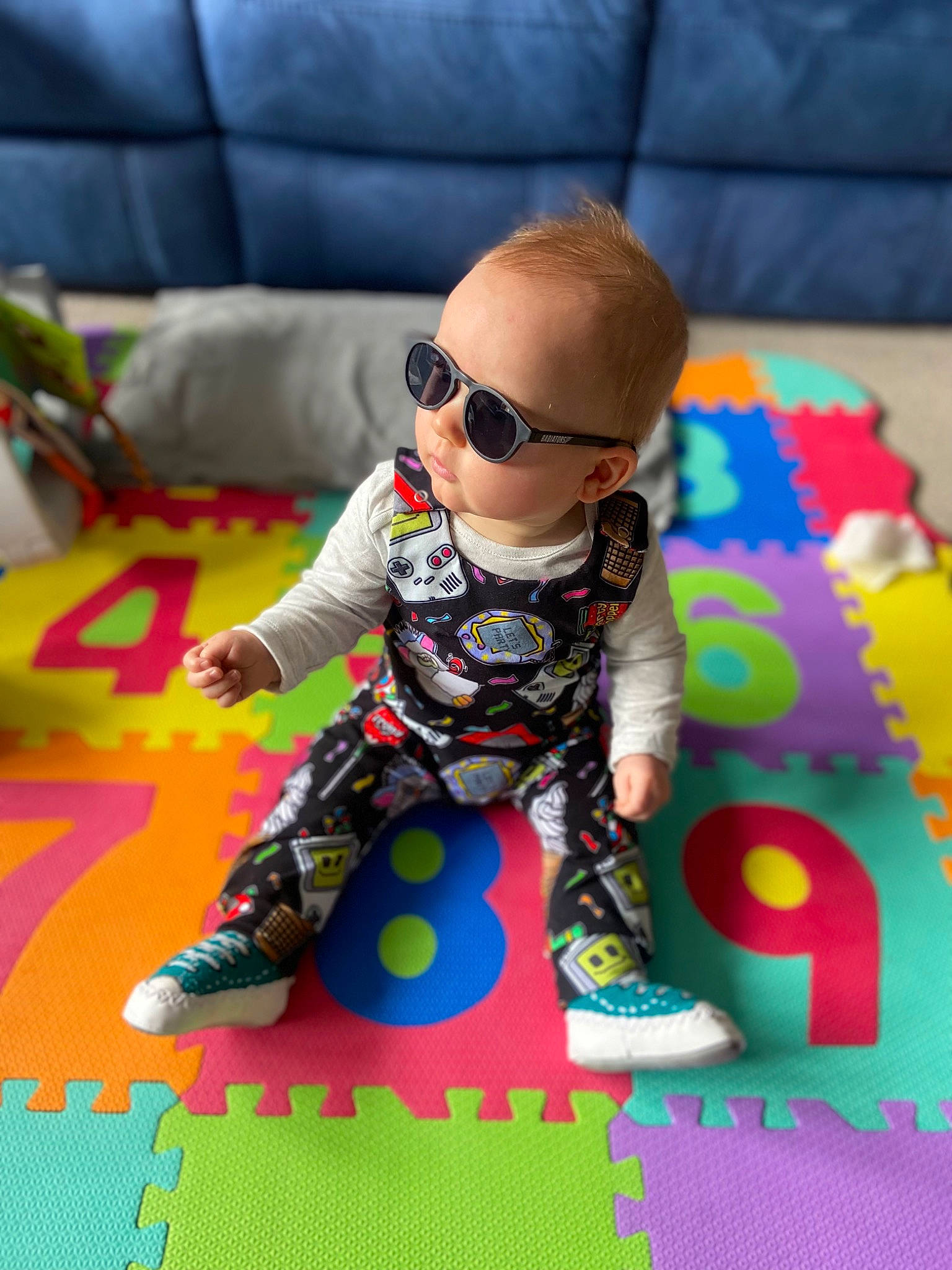 Alfred is registered to the contest to win money with this photo: baby, baby_toddler_clothing, child, eyewear, floor, flooring, fun, glasses, goggles, grass, leisure, mammal, pattern, person, pink, product, purple, sunglasses, textile, toddler