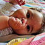 baby, infant, thumb_sucking, close_up, curly_hair, blanket, striped_blanket, sleepwear, cute, child, face, skin, hand, lying_down, indoors, soft_light, expression, comfort, young_child, portrait
