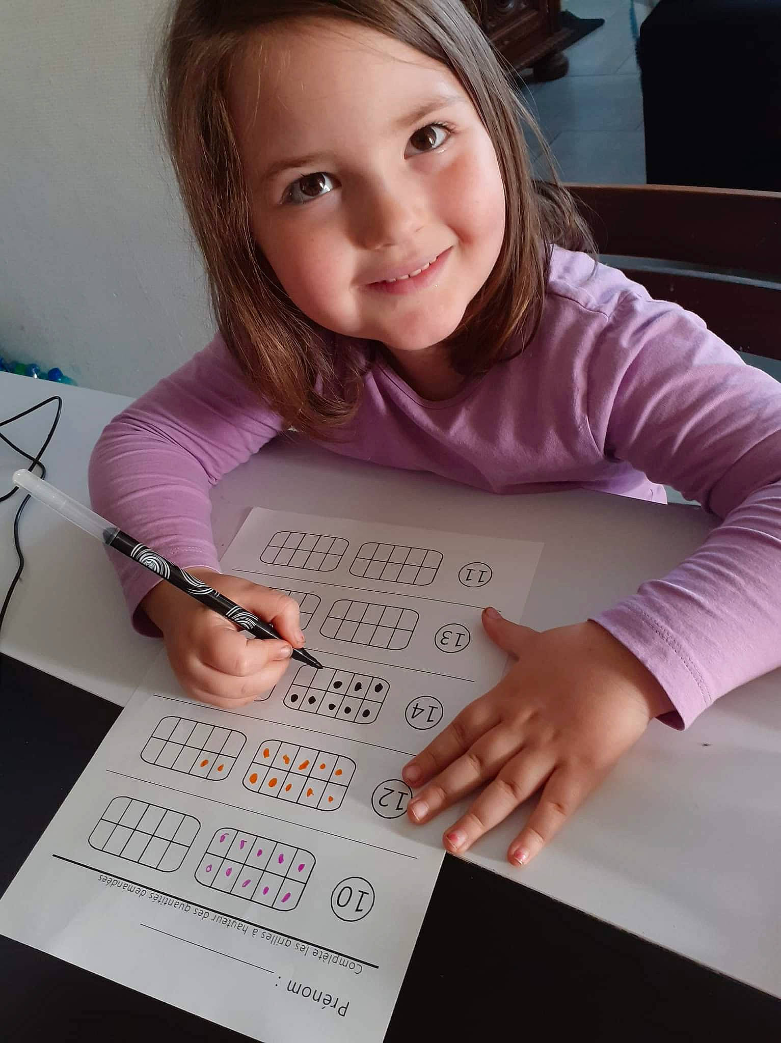 Julie participe au concours pour gagner de l'argent avec cette photo : child, finger, font, fun, handwriting, homework, job, joy, learning, nail, office_instrument, person, purple, reading, room, sitting, smile, stationery, table, toddler