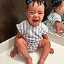 baby, child, smiling, laughing, mirror, reflection, blue_hair_ties, curly_hair, striped_clothing, white_surface, indoor, cute, happy, sitting, portrait, skin, hand, foot, face, expression