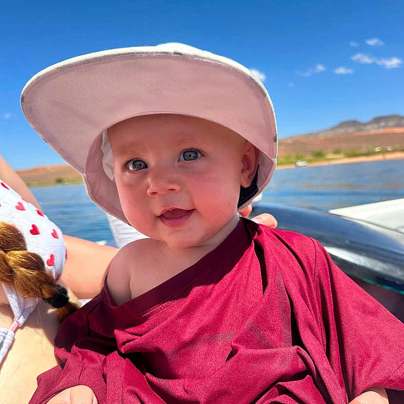 Octavia is registered to the contest to win money with this photo: baby, blue_sky, boat, child, clothing, daylight, face, happy, hat, headwear, landscape, nature, outdoor, person, portrait, sky, smile, summer, sunny, water