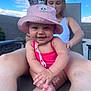 Octavia joined the competition — help win amazing prizes! baby, smiling, pink_hat, pink_swimsuit, outdoor, child, person, happy, sitting, feet, hands, adult, woman, nature, sky, blue_sky, palm_tree, relaxation, sunlight, portrait