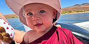 Octavia is registered to the contest to win money with this photo: baby, child, hat, smile, outdoor, water, sky, sunny, clothing, person, face, happy, nature, summer, portrait, boat, landscape, headwear, daylight, blue_sky