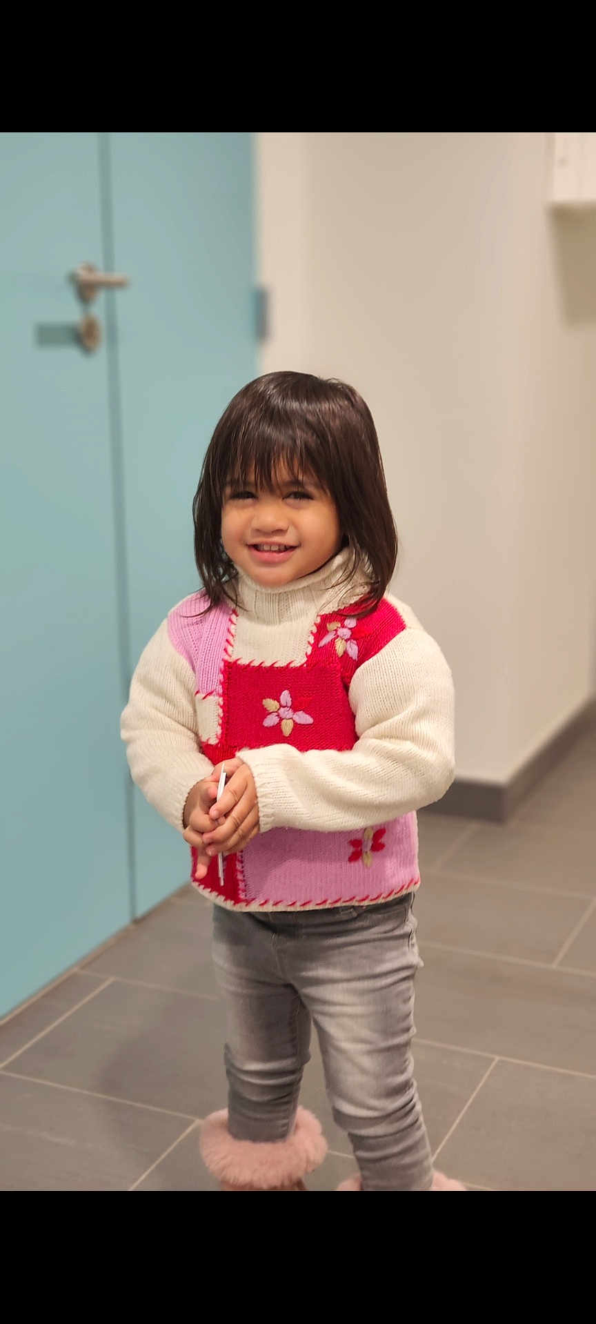 Titaina a rejoint le concours — aidez-le/la à gagner de superbes lots ! child, smiling, indoor, sweater, flower_pattern, jeans, boots, floor, door, happy, person, tiled_floor, casual_clothing, cute, portrait, standing, young_child, long_hair, warm_clothing, cozy