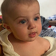 Denny is registered to the contest to win money with this photo: baby, child, face, blue_eyes, curious, close_up, skin, texture, cloth, white, indoor, portrait, expression, soft_light, human, infant, head, cute, person, young