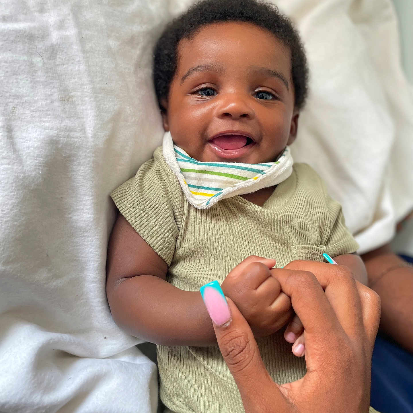 Nyjour is registered to the contest to win money with this photo: baby, child, smiling, hand, blanket, clothing, face, portrait, cute, infant, person, nail_polish, skin, happy, holding, closeup, indoors, fabric, toddler, expression