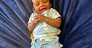 Nyjour is registered to the contest to win money with this photo: baby, child, smiling, laughing, blue_clothing, shorts, tshirt, lying_down, fabric, plush, happy, infant, person, cute, indoor, young_child, skin, head, hands, legs