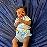 baby, child, smiling, laughing, blue_clothing, shorts, tshirt, lying_down, fabric, plush, happy, infant, person, cute, indoor, young_child, skin, head, hands, legs